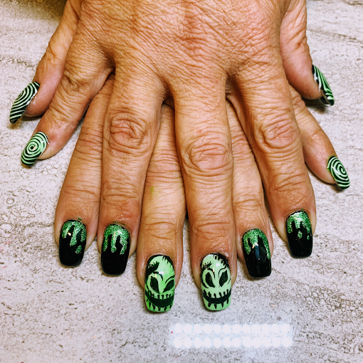 Halloween-themed green and black nail art with alien designs and glitter drip accents