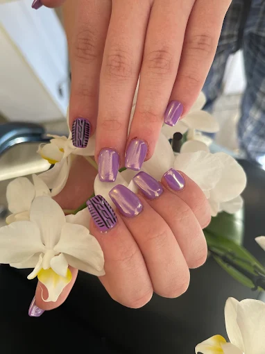 Lavender chrome nails with dark tribal pattern accent nails styled with white orchids